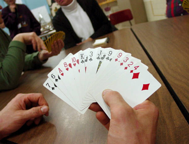 folks playing cards with a close up of one players hand